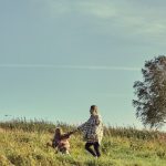 A mother and daughter holding hands, enjoying a sunny day on the farm landscape.