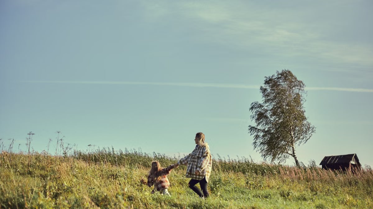 A mother and daughter holding hands, enjoying a sunny day on the farm landscape.